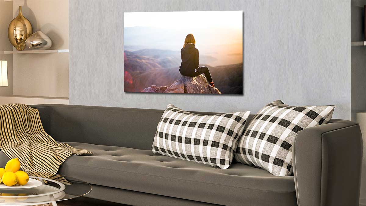 A1 photo poster of a woman sitting atop a mountain on a wall above a sofa