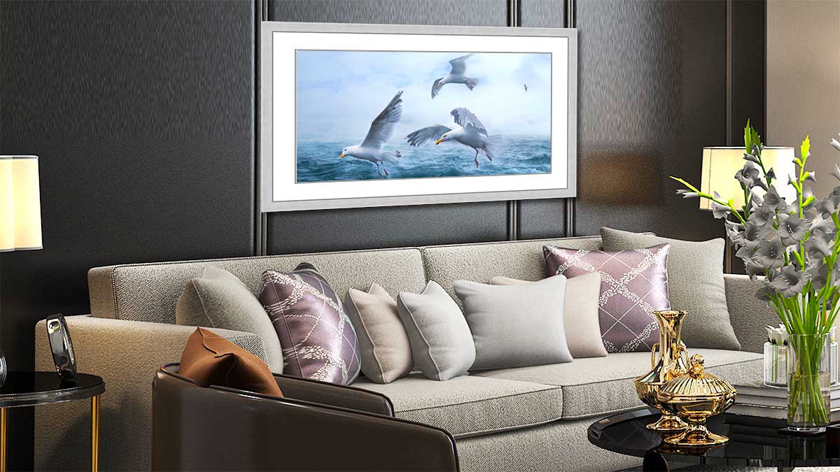 Framed poster featuring a seascape with gulls hung over an elegant settee