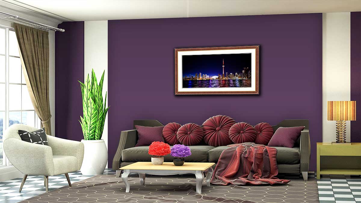 Framed panoramic photo of a city at night hung on a purple wall